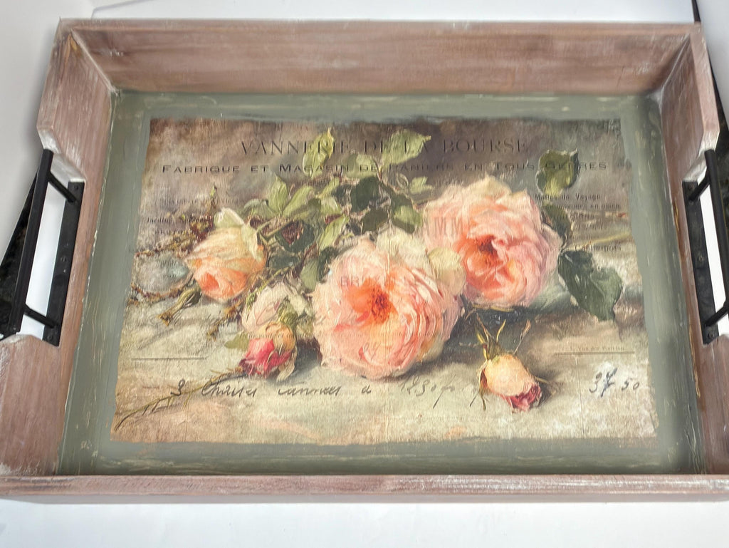 a wooden tray with a framed painting of pink roses on it.