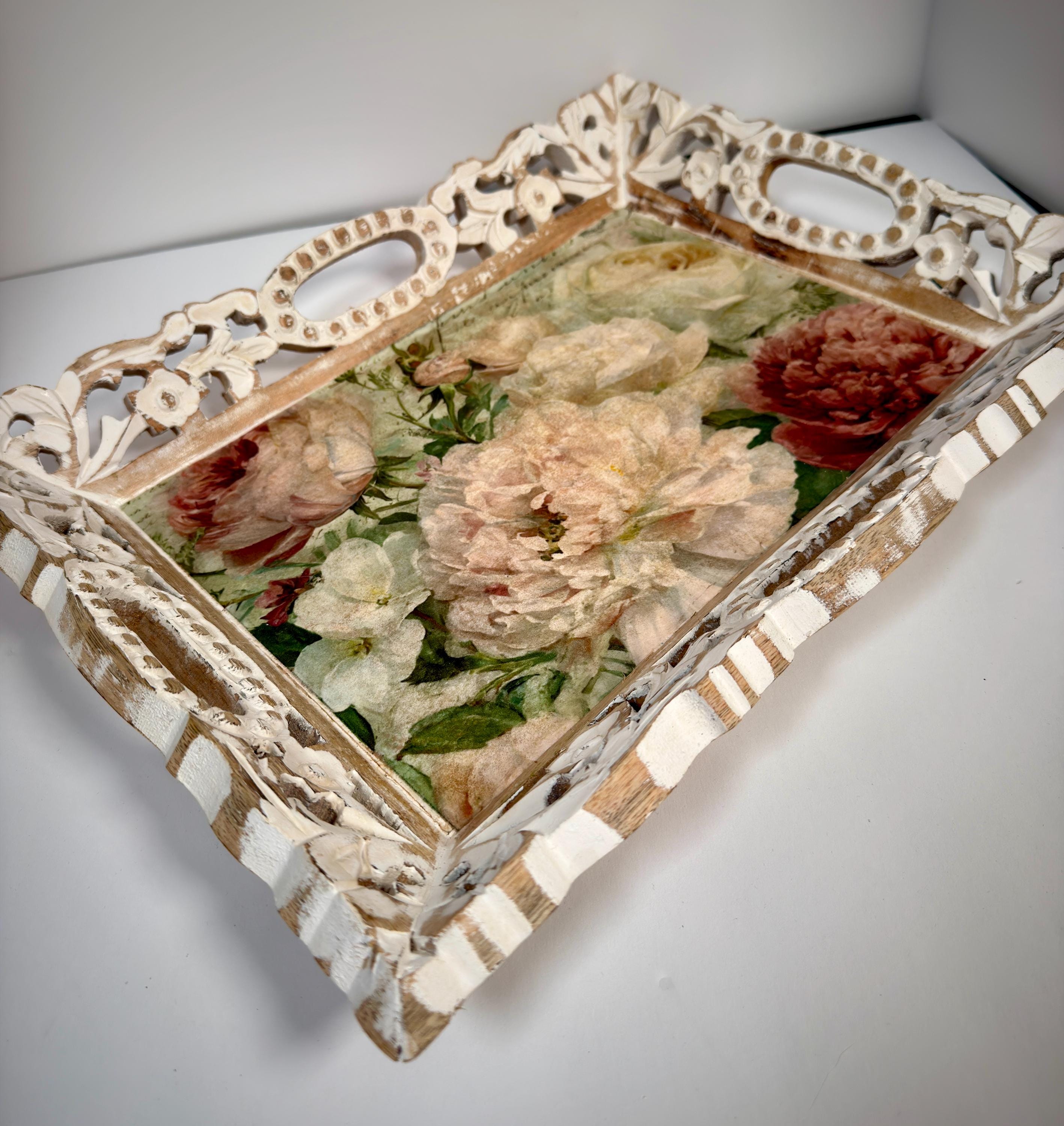 A decorative wooden tray with a floral design on the front, featuring a variety of colorful flowers.