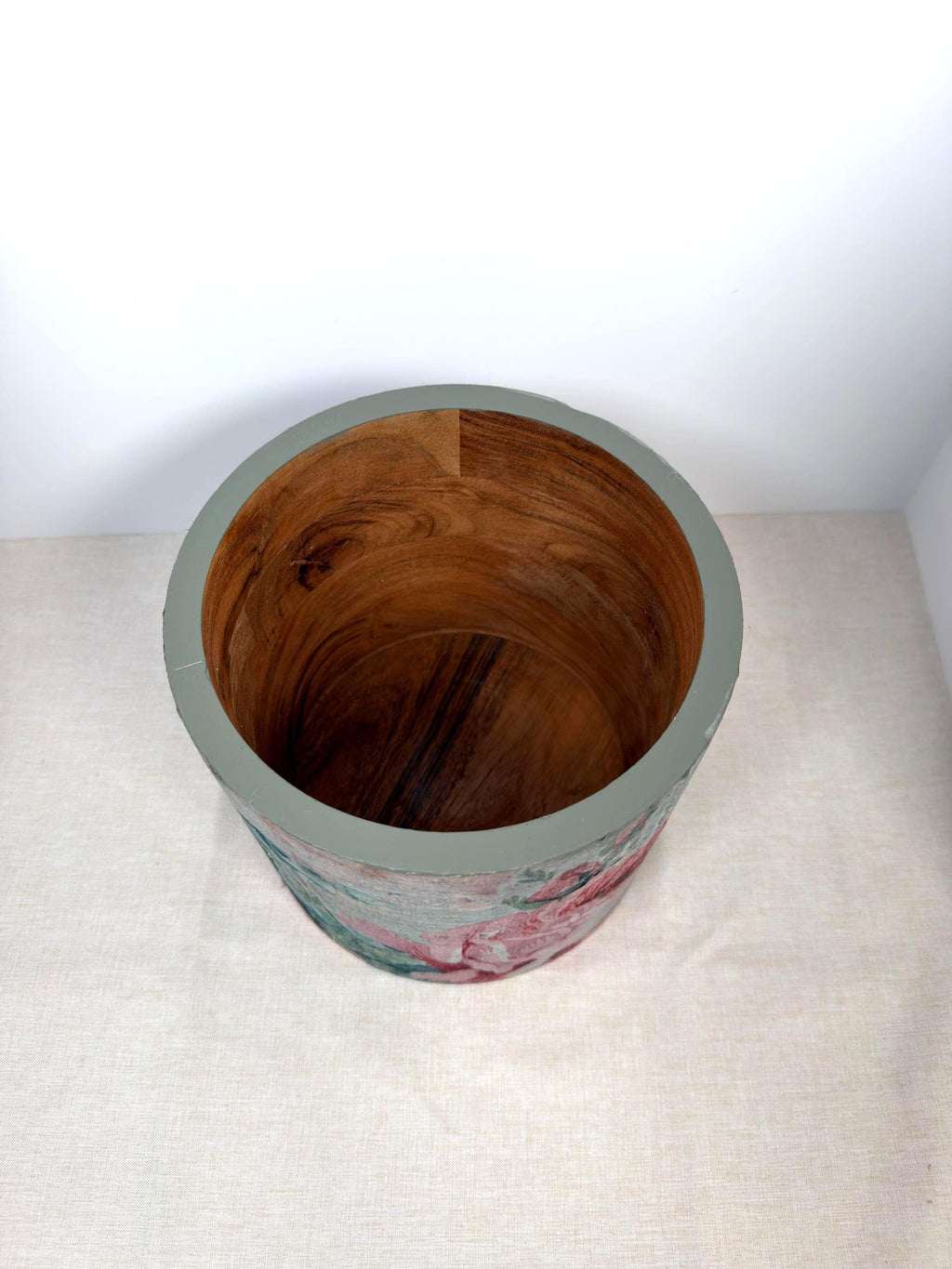 a wooden bowl with a floral pattern on it, sitting on a white surface.