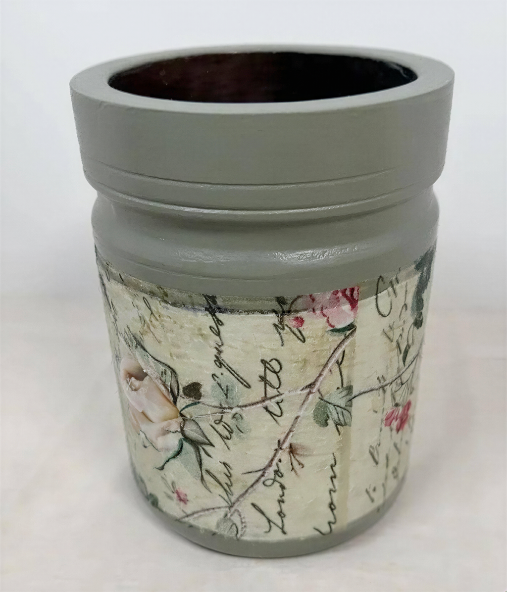 a gray vase with a floral pattern and some text printed on it.