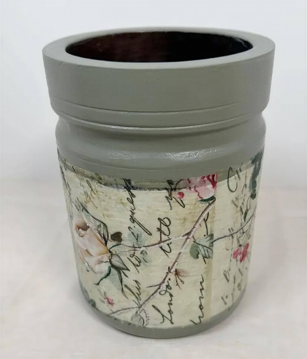 a gray vase with a floral pattern and some text printed on it.