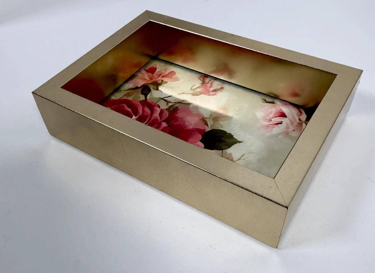 A gold-colored box with a floral pattern inside, placed on a white surface.