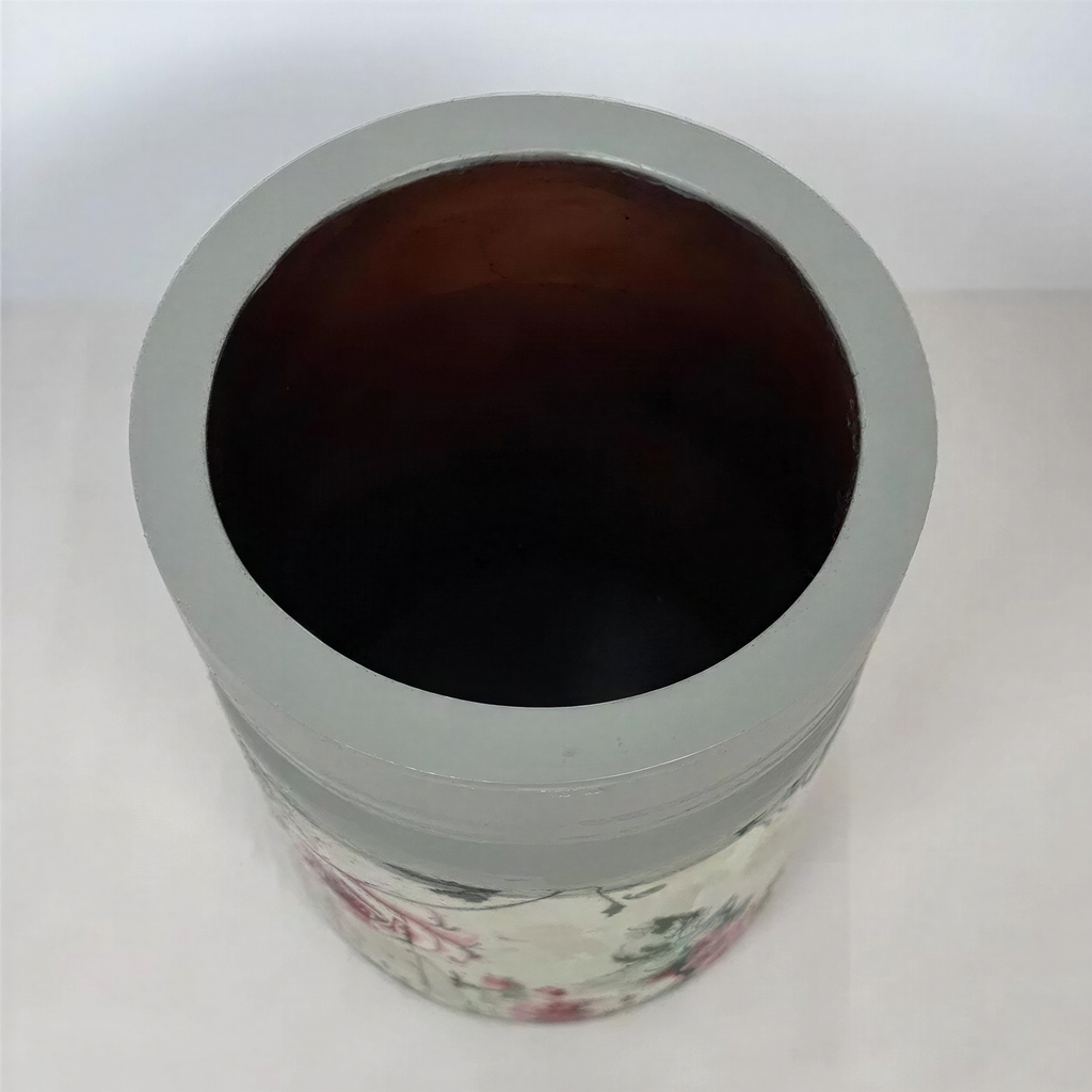 A gray vase with a floral pattern on it, sitting on a white surface.