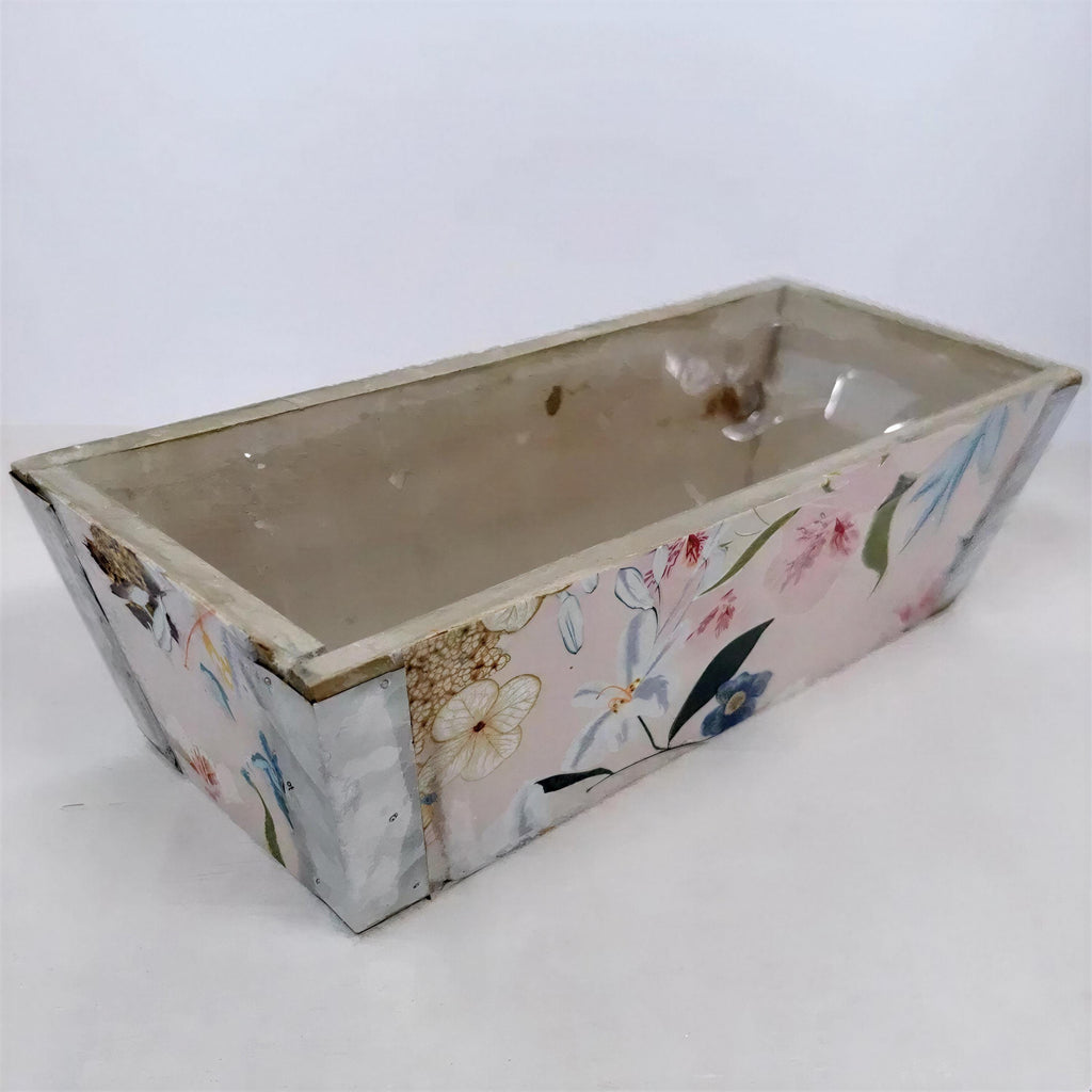 A rectangular planter box with a floral pattern on its sides, sitting on a white surface.