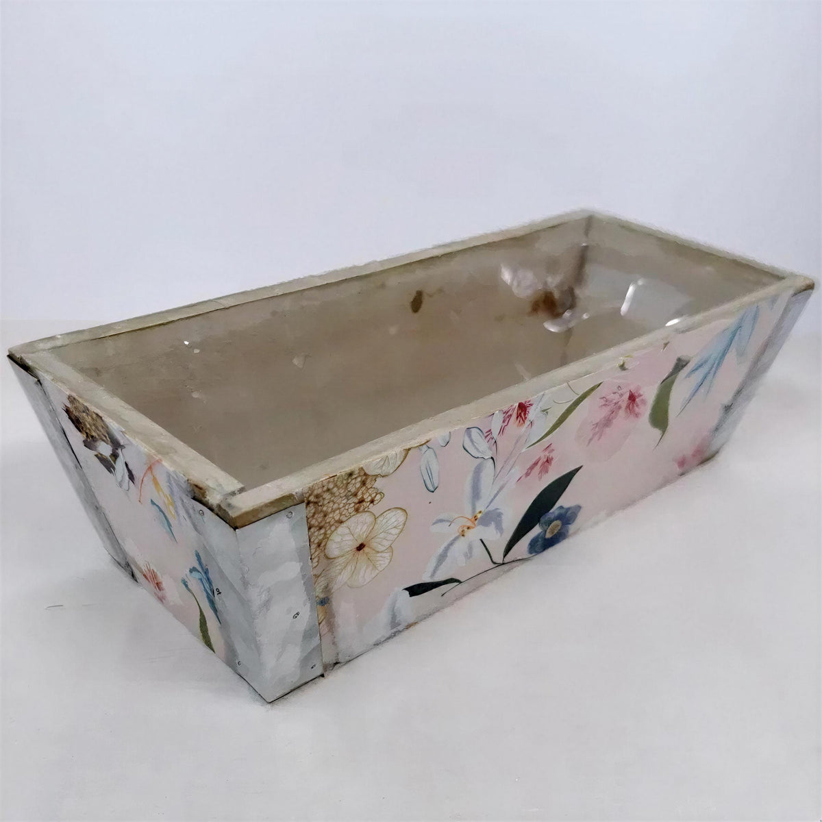 A rectangular planter box with a floral pattern on its sides, sitting on a white surface.