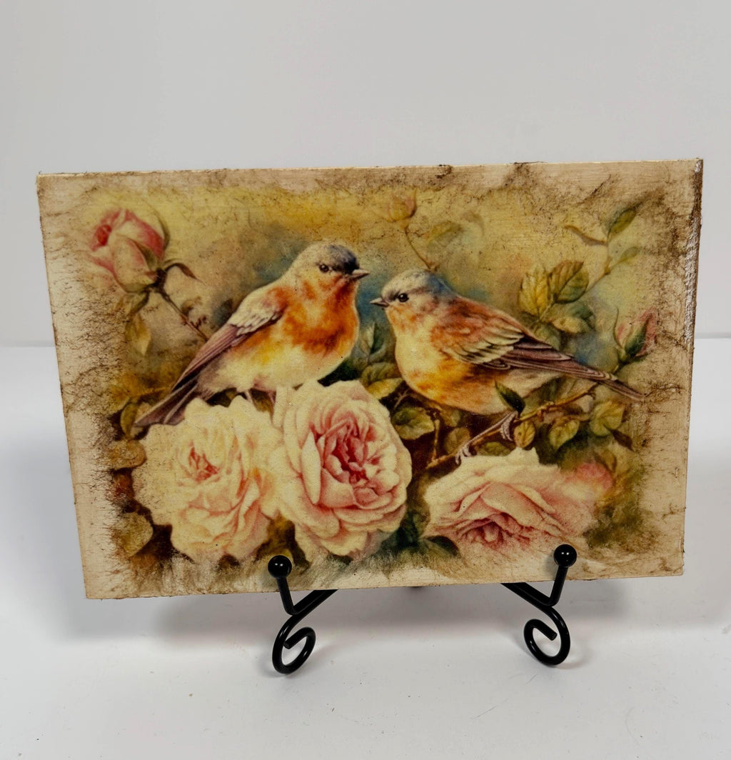 a painting of two birds perched on branches with pink roses in the background.