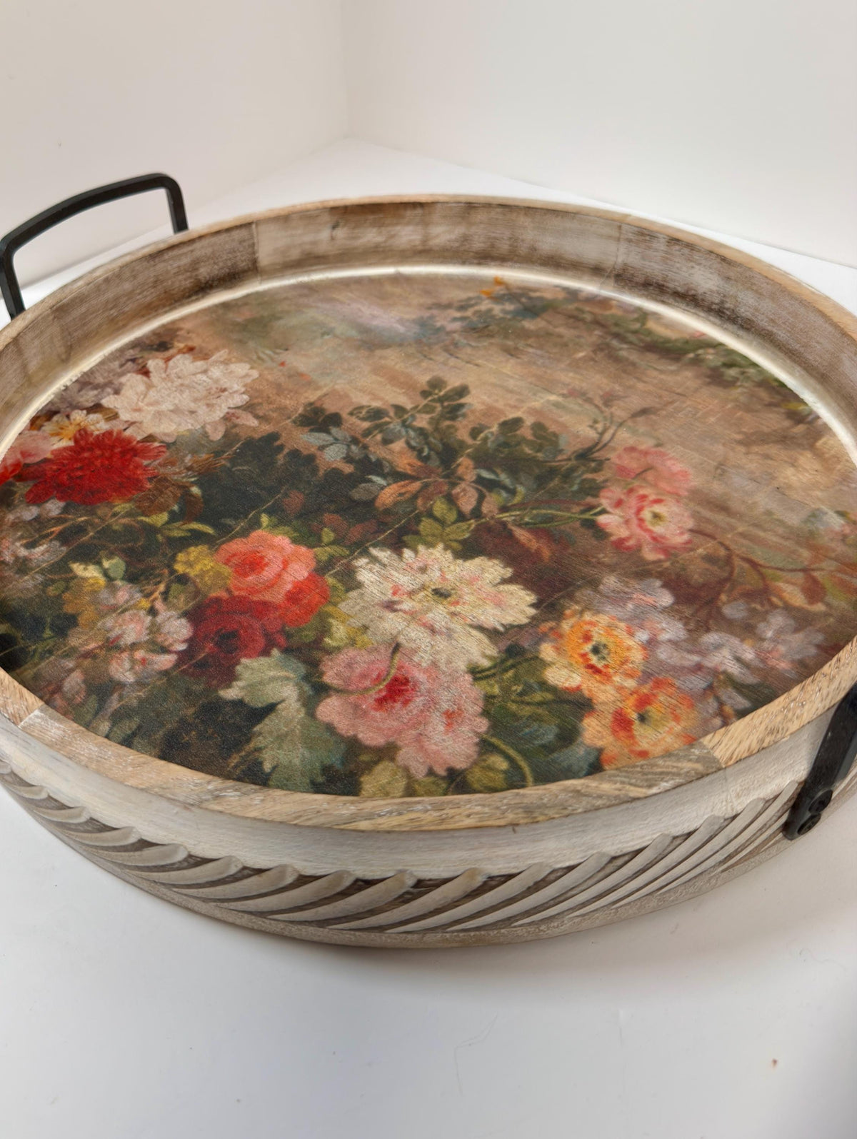 A round wooden tray with a floral design on it, featuring a variety of colorful flowers and leaves.
