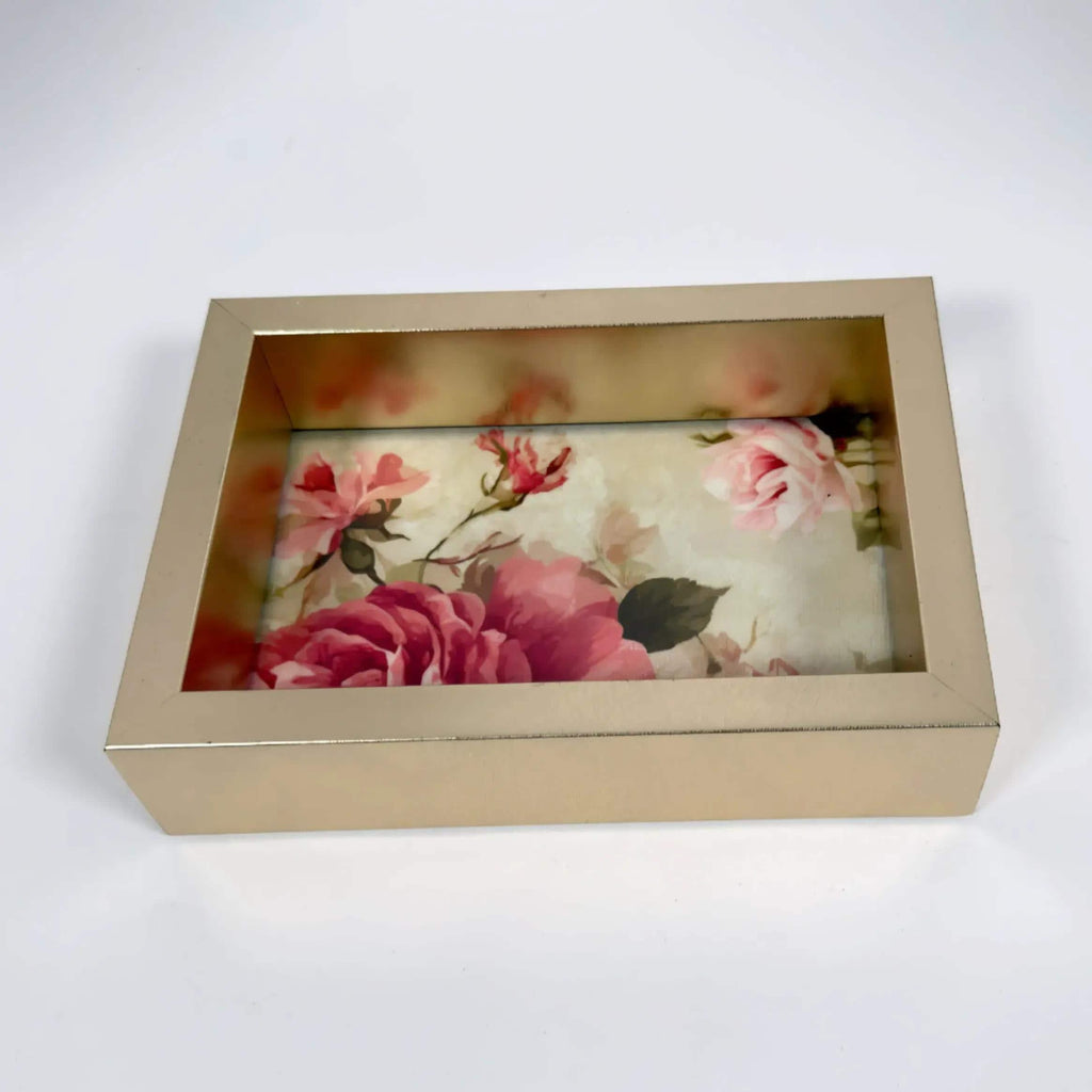 a gold-colored rectangular box with a floral design on the front, showcasing a variety of pink and red flowers.