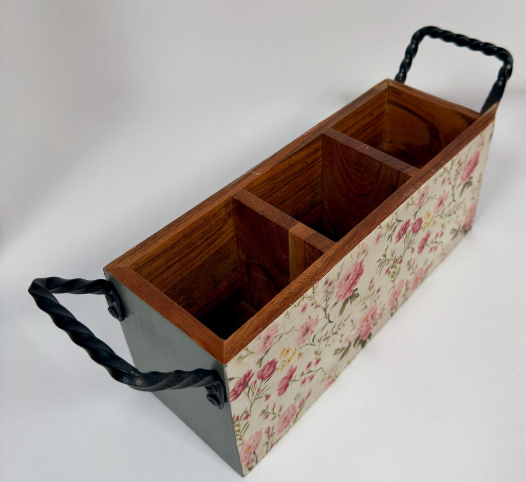 A wooden box with a floral pattern on the front, featuring two black handles.