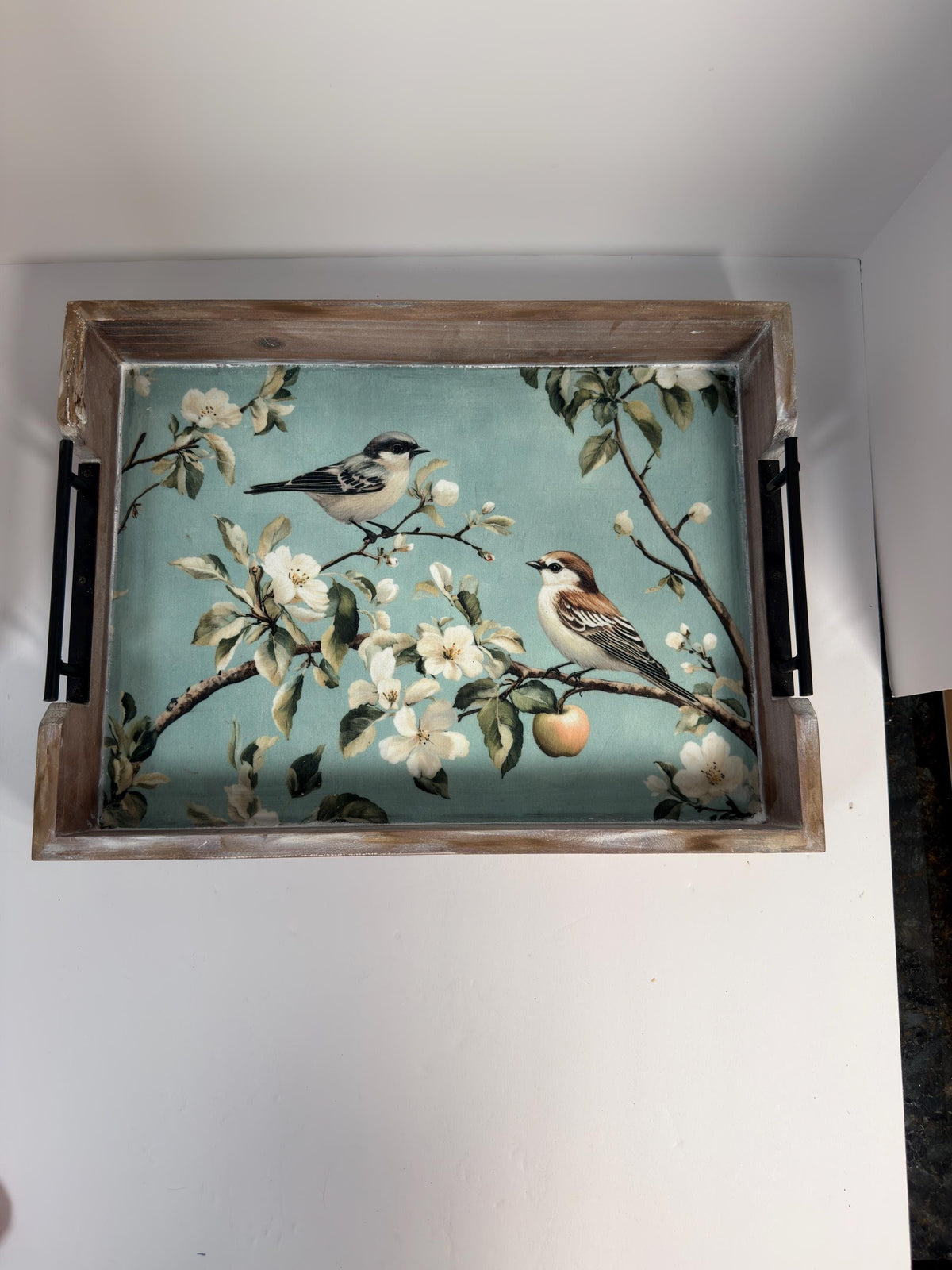 A wooden tray with a floral design featuring two birds perched on branches with white flowers.