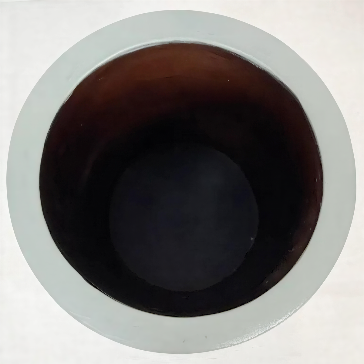 a white bowl with a dark brown interior, placed on a white surface.