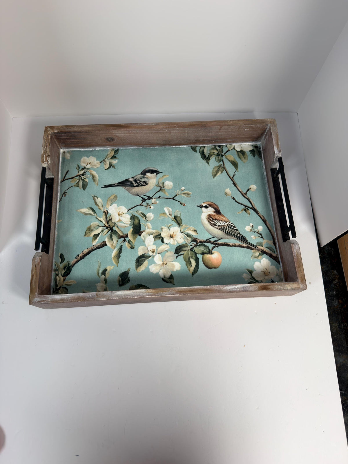 A wooden tray with a floral design featuring two birds perched on branches with white flowers.