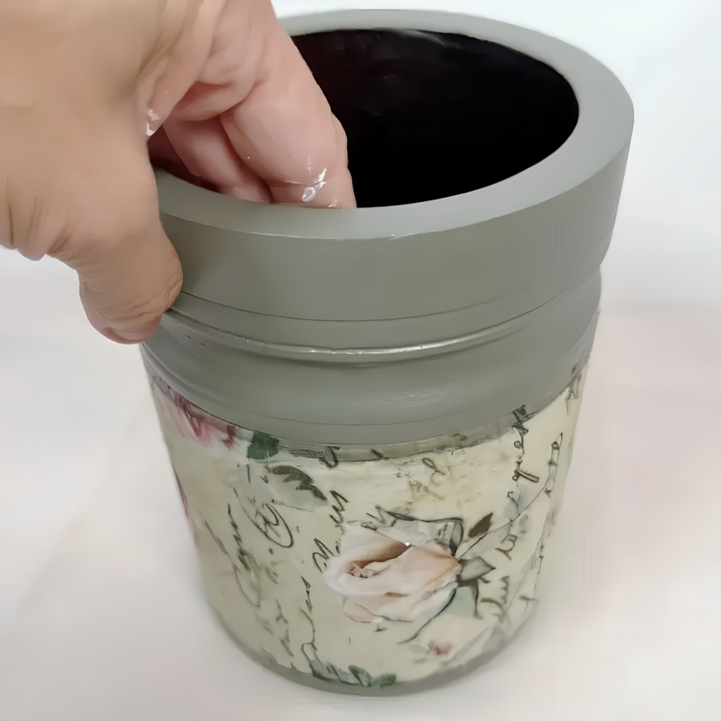 A hand is reaching into a gray vase with a floral pattern on it.