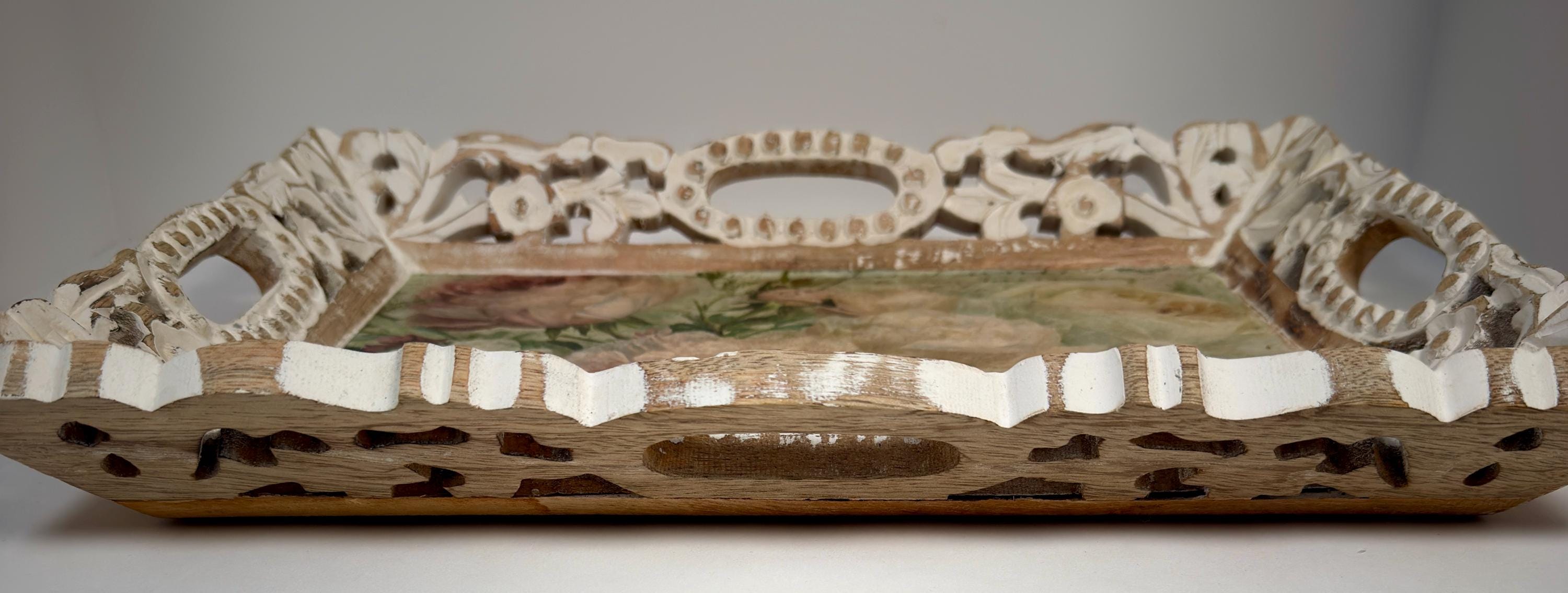 A decorative wooden tray with intricate carvings and a floral pattern on the surface.