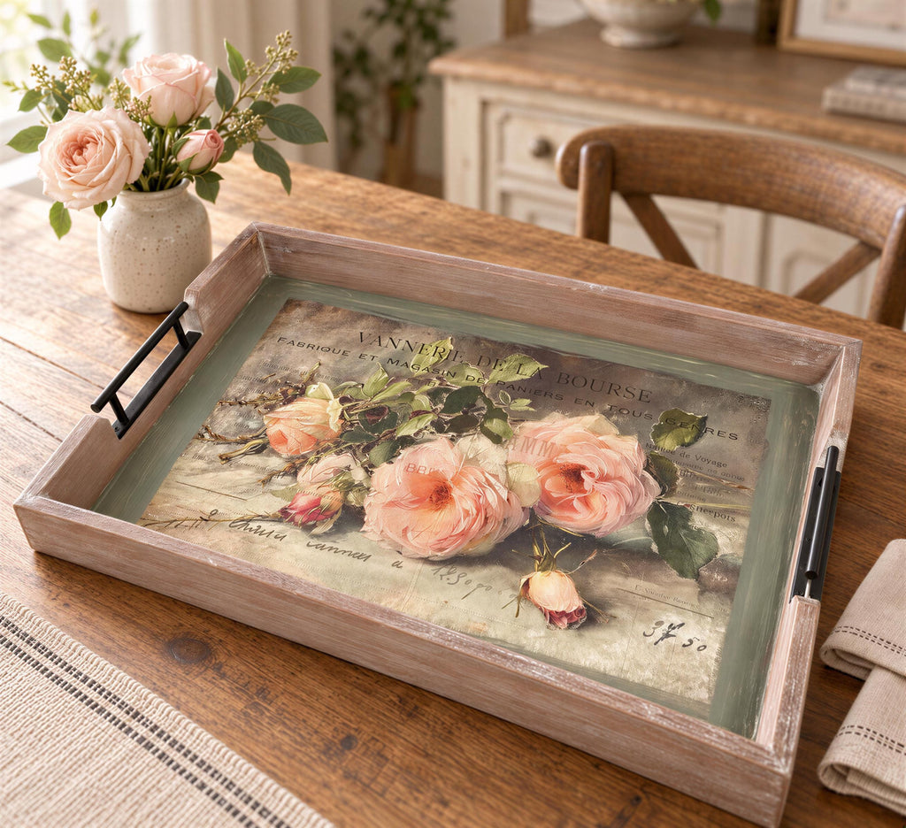 a wooden tray with a floral design, placed on a wooden table. The tray has a vase of pink roses and a potted plant nearby.