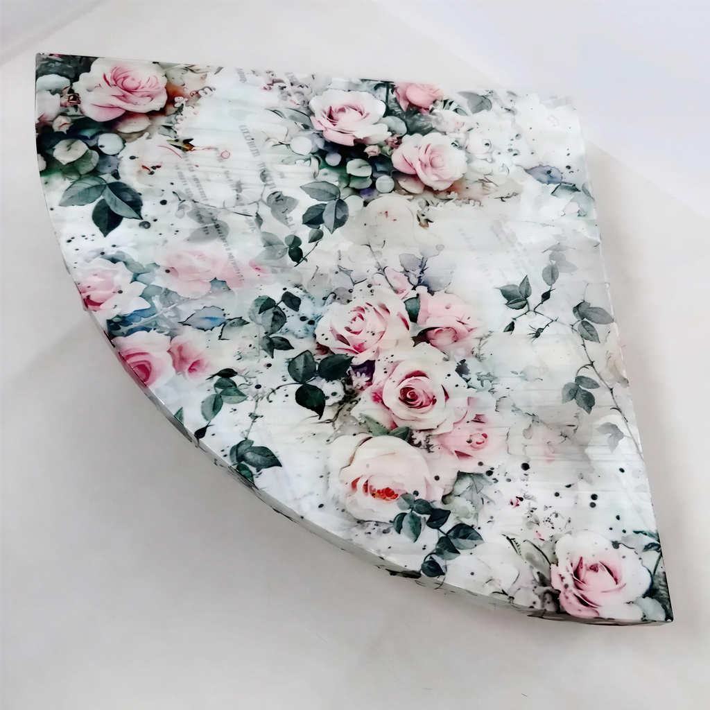 a decorative piece with a floral pattern, including pink and white roses, along with green leaves. The piece appears to be a decorative item, possibly a vase or a sculpture, with a floral design.