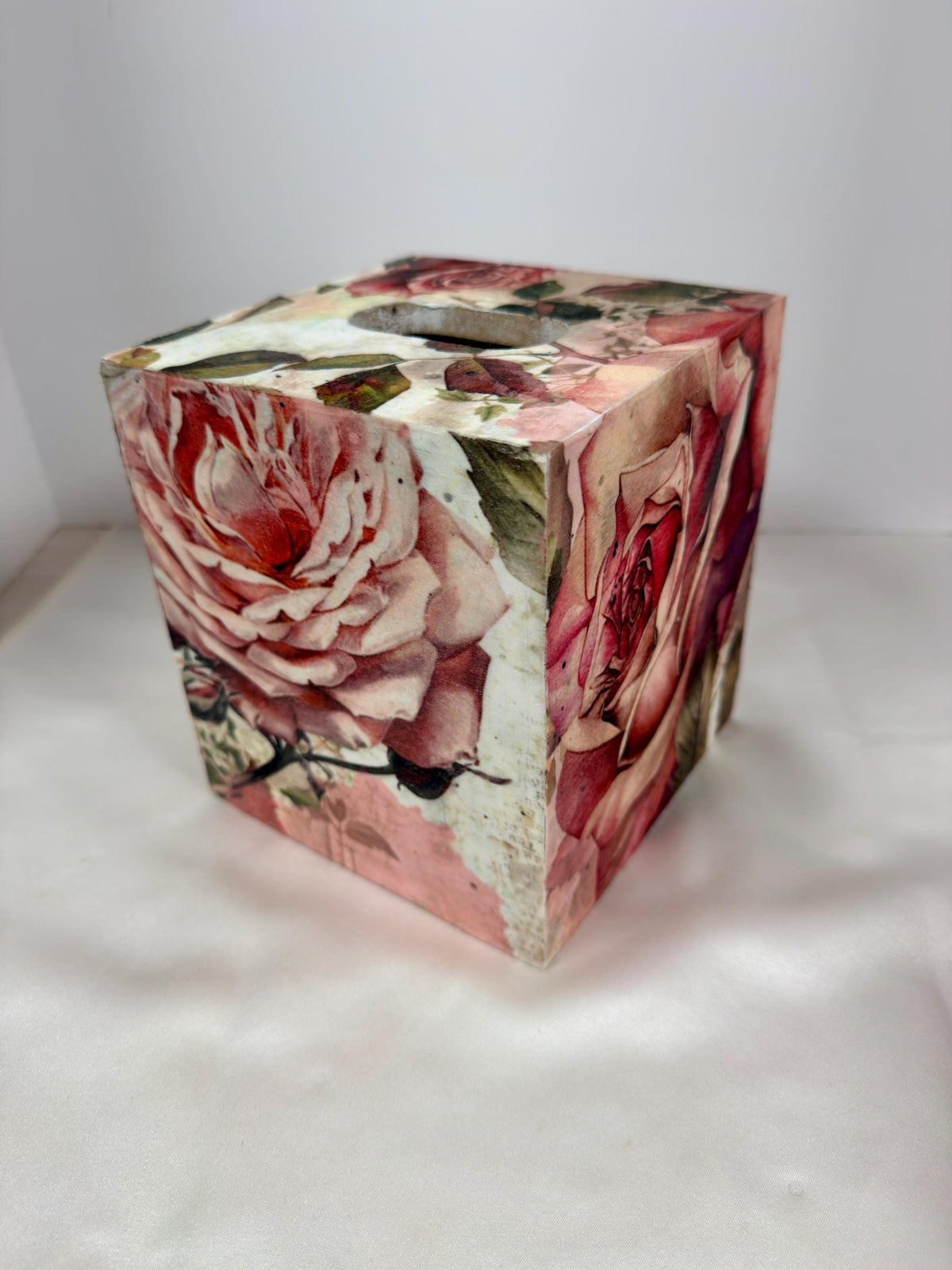 A decorative box cover with a floral pattern featuring pink and red roses.