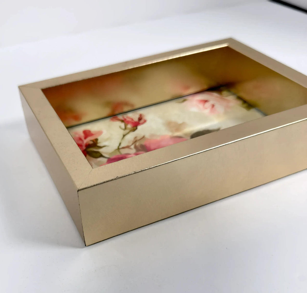 A gold-colored box with a floral pattern inside, sitting on a white surface.