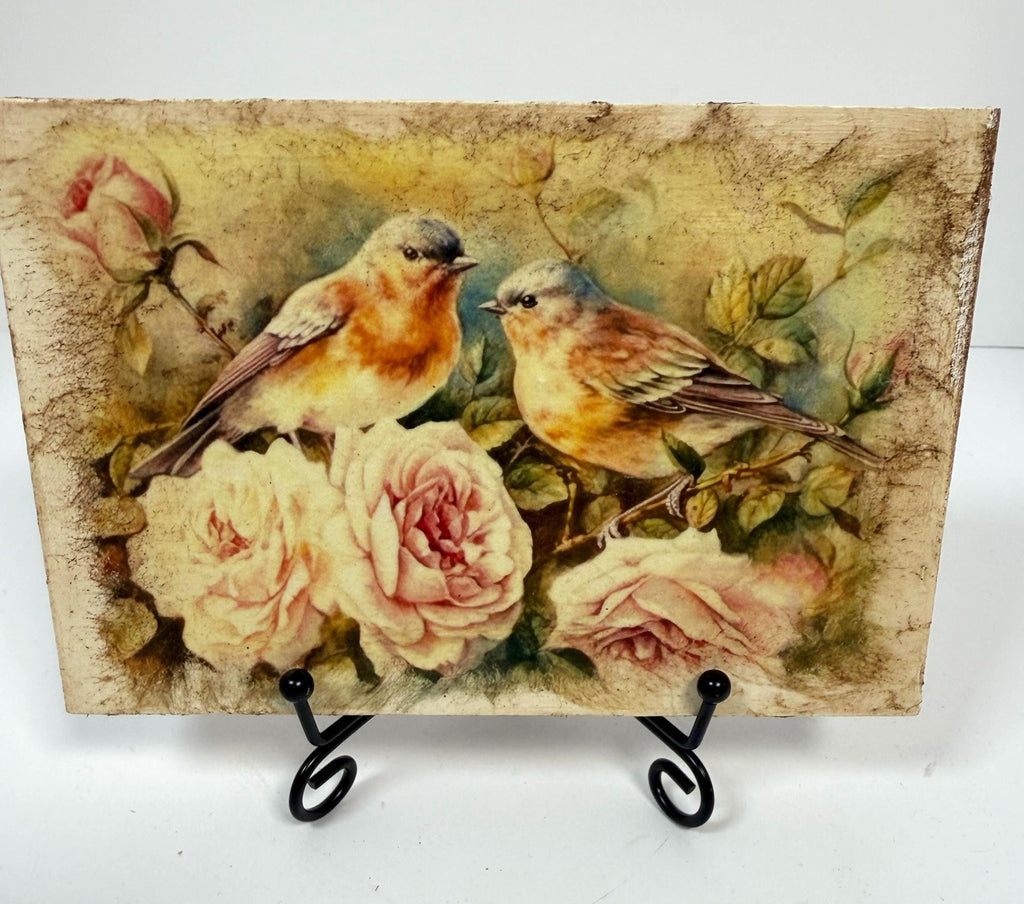 two birds perched on a branch with pink roses, surrounded by lush greenery.