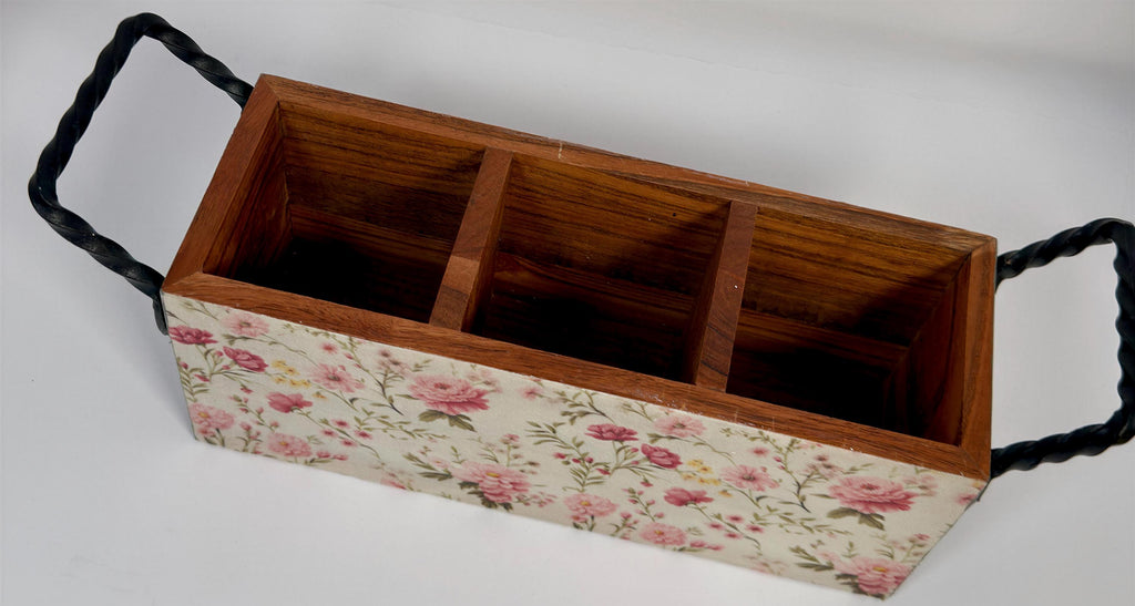 A wooden box with three compartments, each with a black metal handle, and a floral pattern on the front.