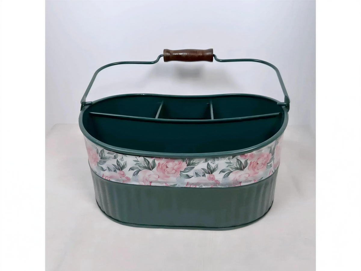 A green metal basket with a floral pattern on the front, featuring a handle and three compartments.
