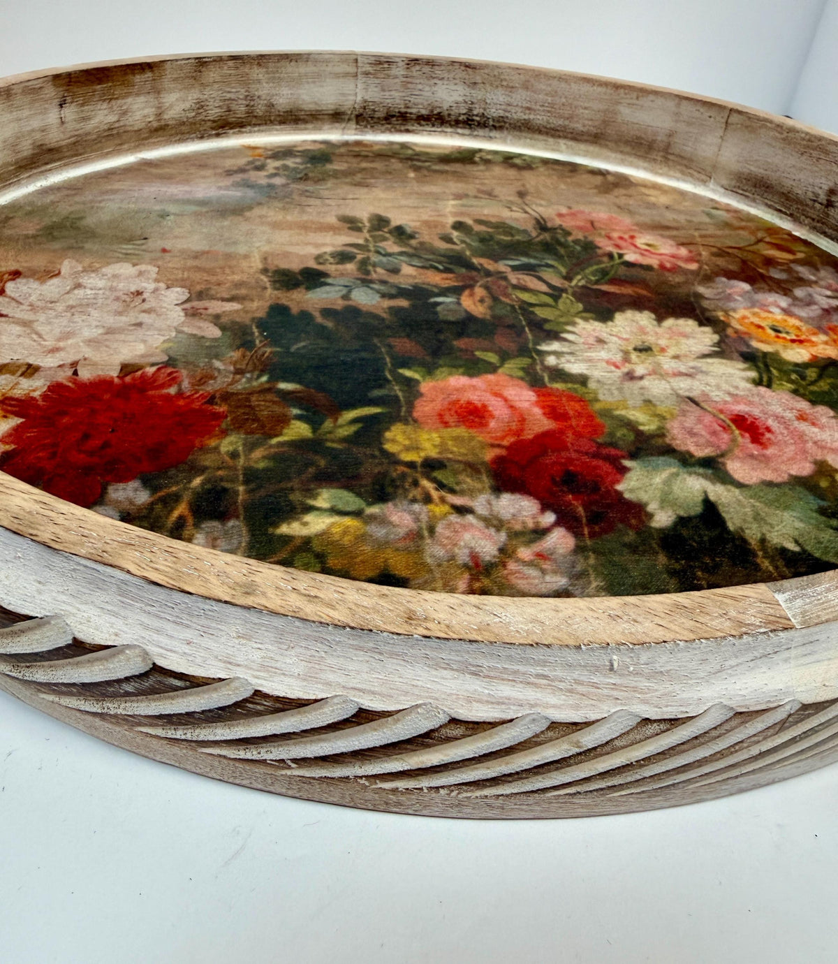 a round wooden tray with a floral design on its surface.