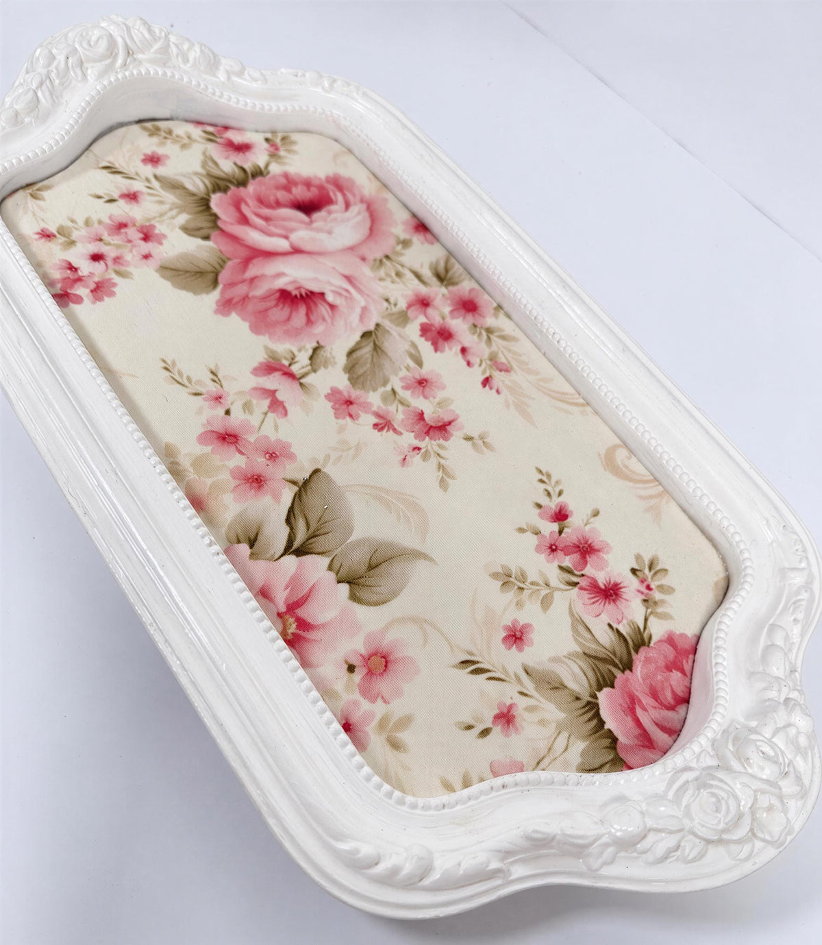 A white decorative tray with a floral pattern on it.