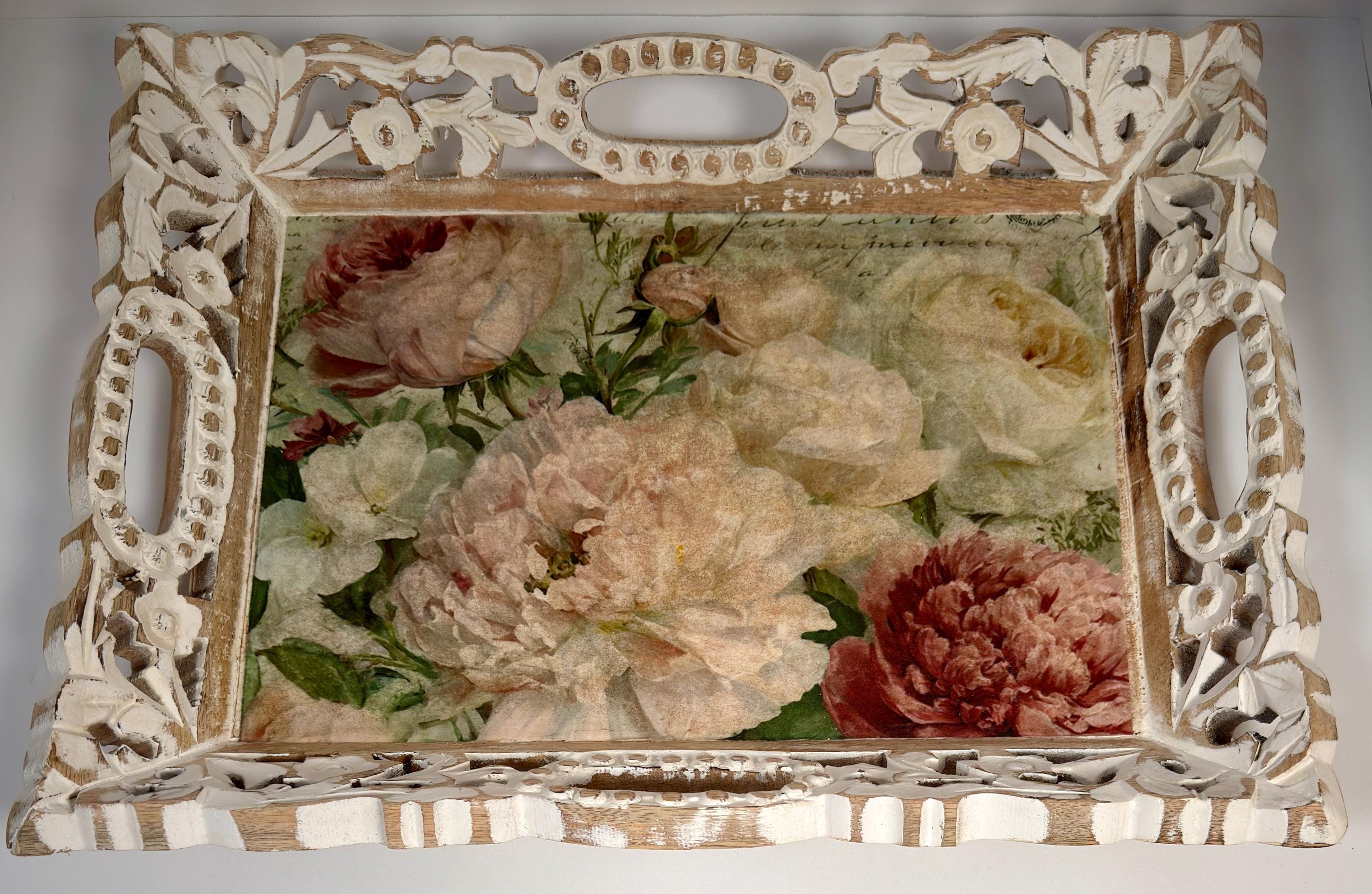 a decorative white tray with an ornate frame, displaying a floral arrangement of various colored flowers, including pink, white, and red blooms.