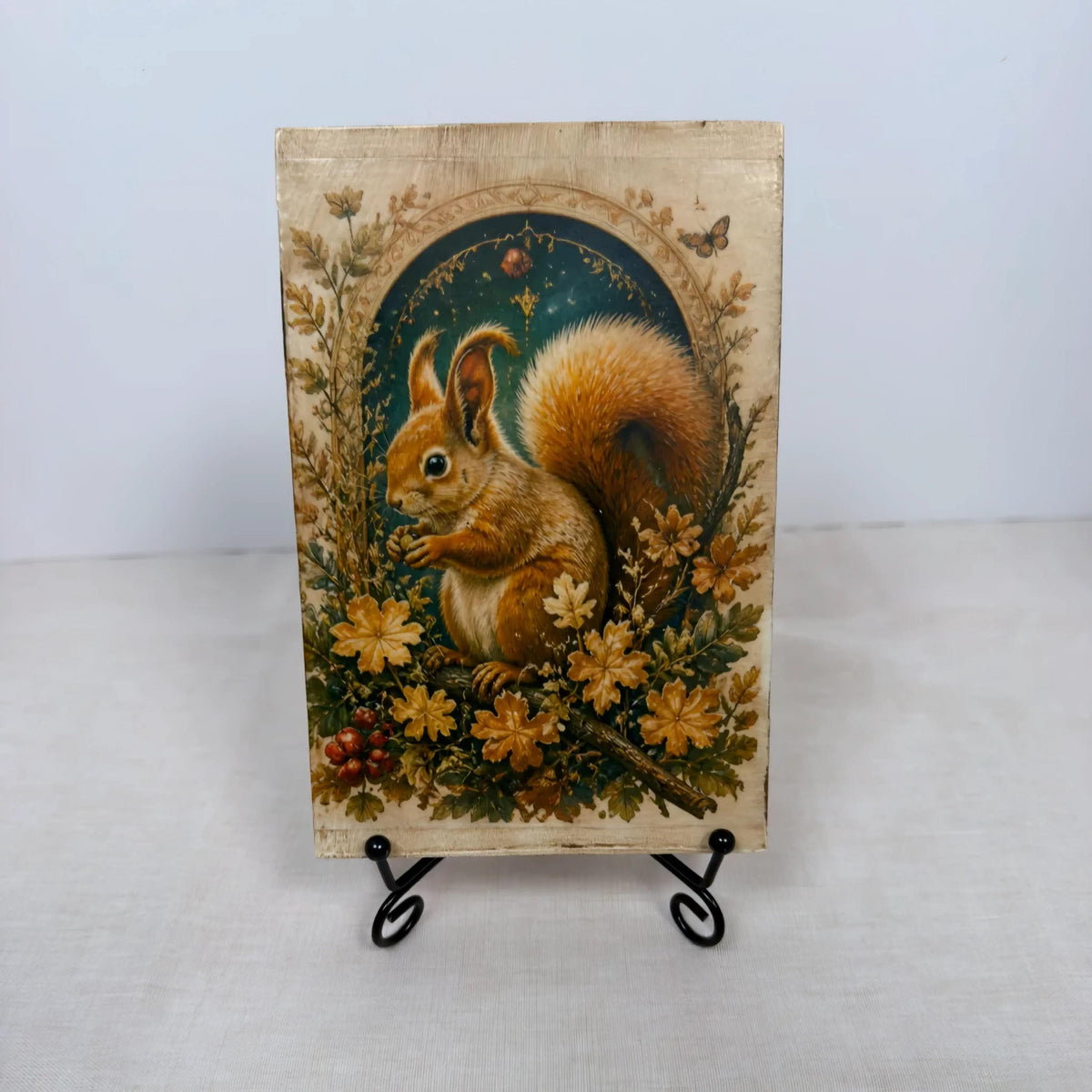 a wooden frame with a painting of a squirrel on it, placed on a stand.