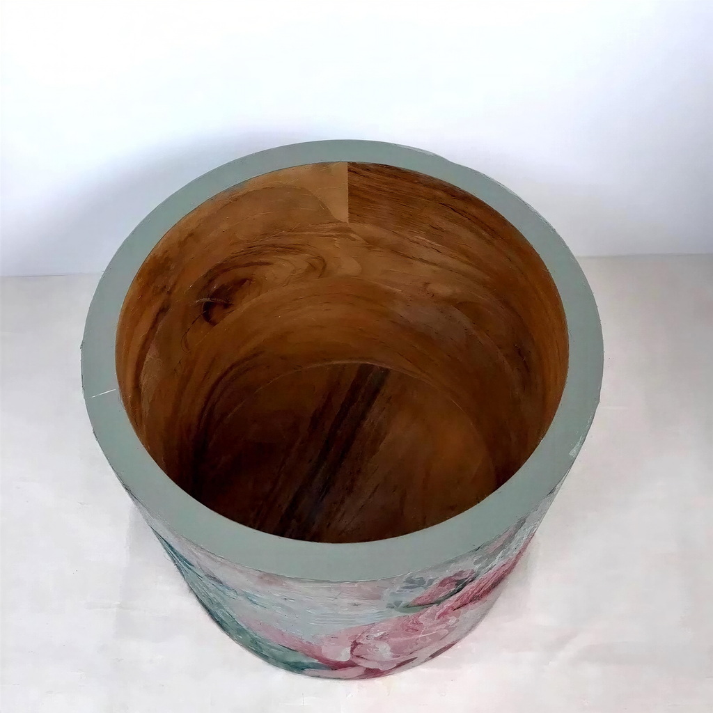a wooden bowl or container with a floral pattern painted on it, sitting on a white surface.