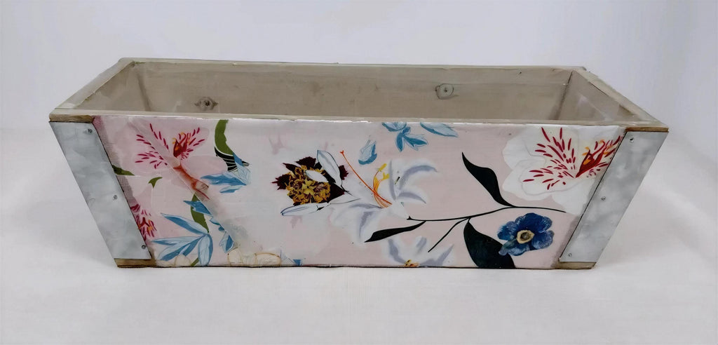 A wooden planter box with a floral pattern painted on it.