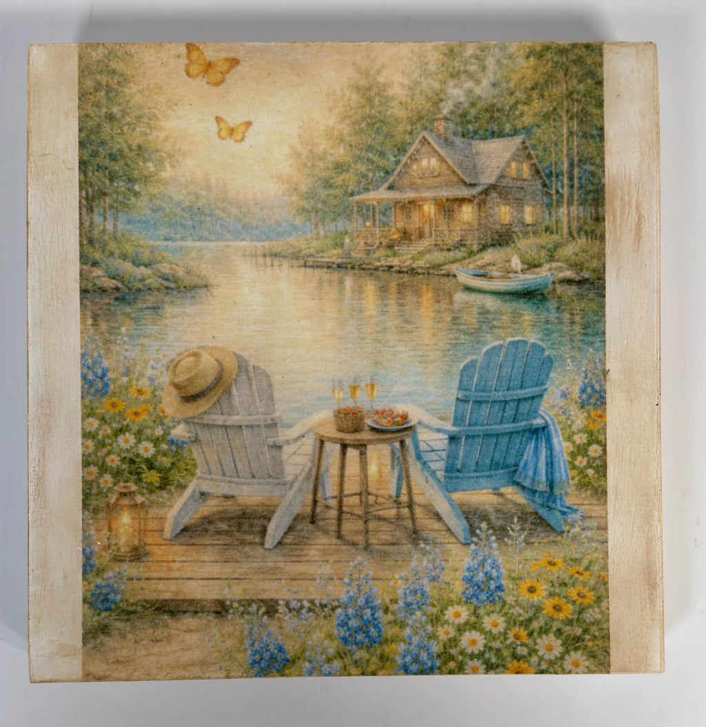 A serene lakeside scene with a cabin, two chairs, and a table set for a peaceful lakeside picnic. Butterflies are seen flying in the sky, and the water reflects the surrounding scenery.